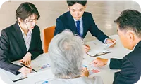 資料を見ながら老夫婦に説明をするスーツの男女